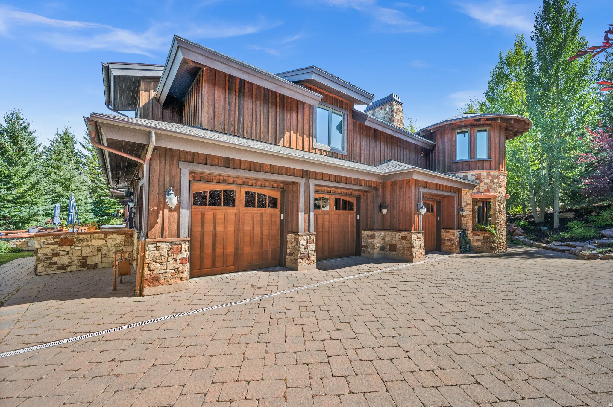View of front facade featuring stone siding, decorative driveway, and an attached garage