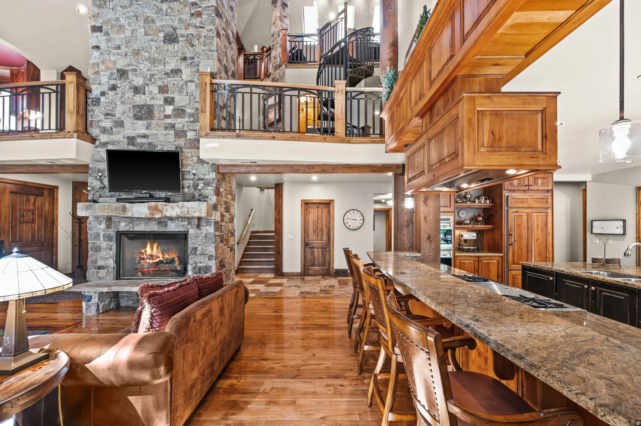 Kitchen with a fireplace, dark stone countertops, a kitchen breakfast bar, vaulted ceiling, and light wood finished floors