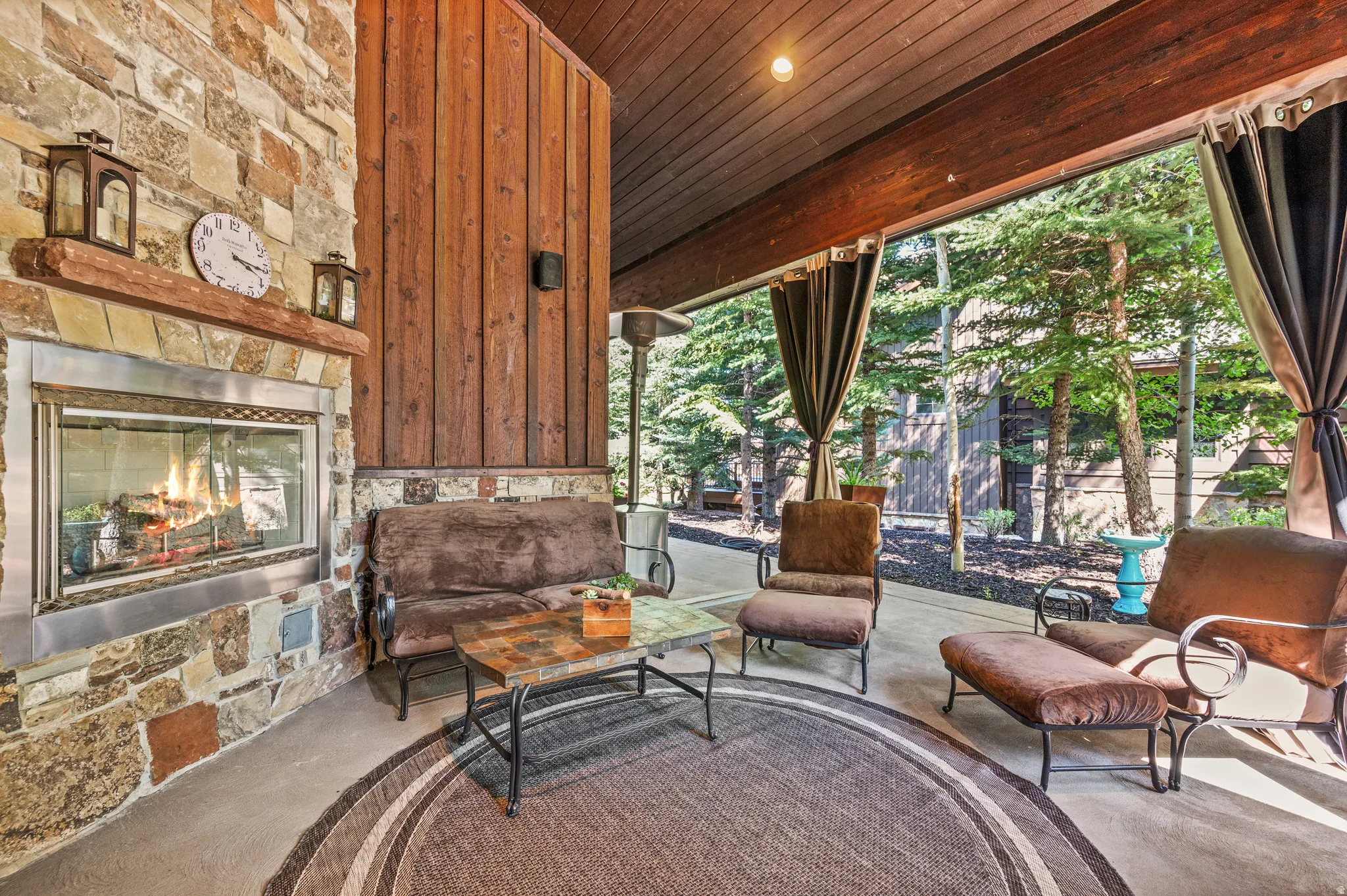 Sitting room featuring an outdoor stone fireplace, wood ceiling, and recessed lighting