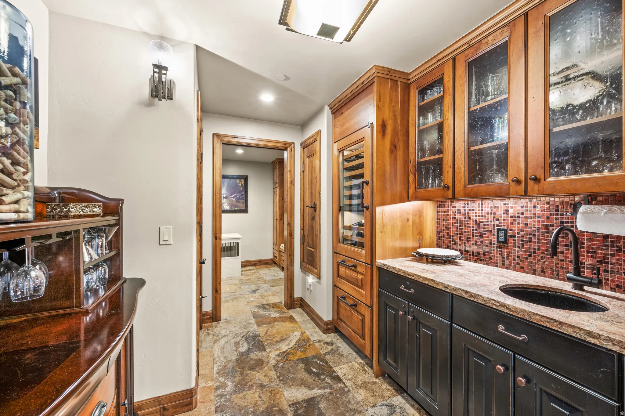 Bar featuring light stone counters, glass insert cabinets, tasteful backsplash, light stone finish floors, and recessed lighting