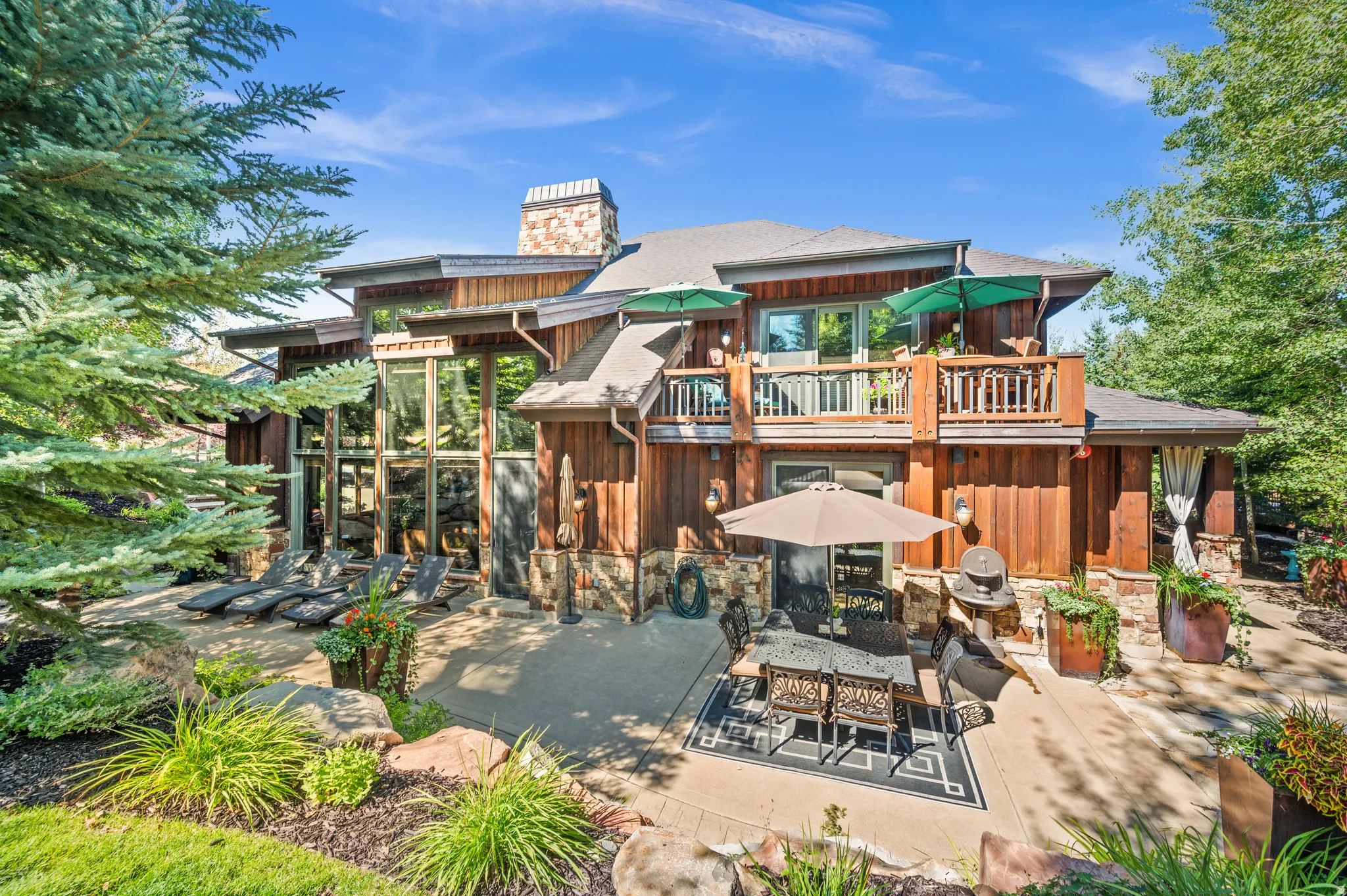 Rear view of house featuring a patio area, board and batten siding, outdoor dining space, and a balcony
