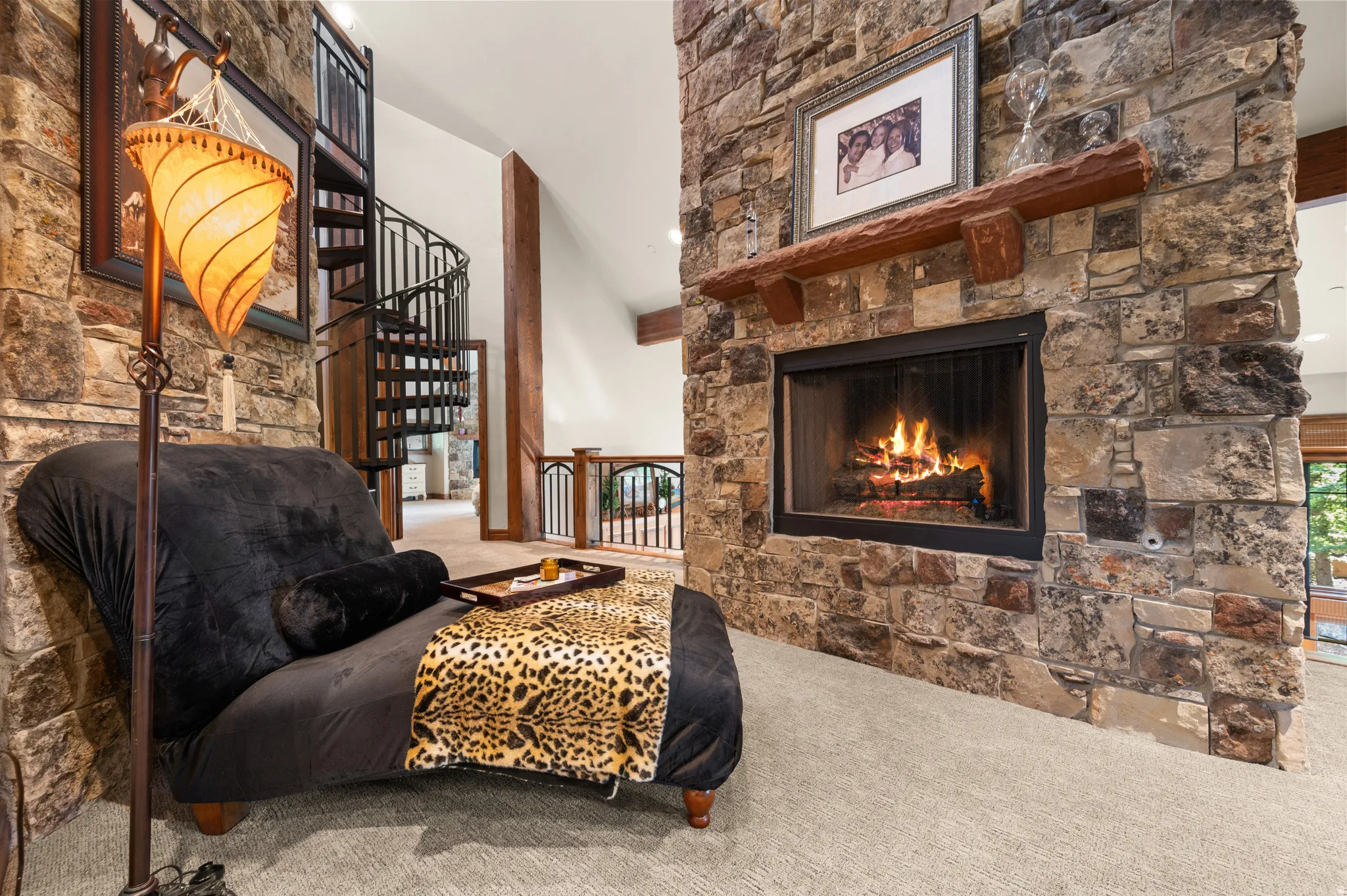Carpeted living area featuring a stone fireplace and a high ceiling