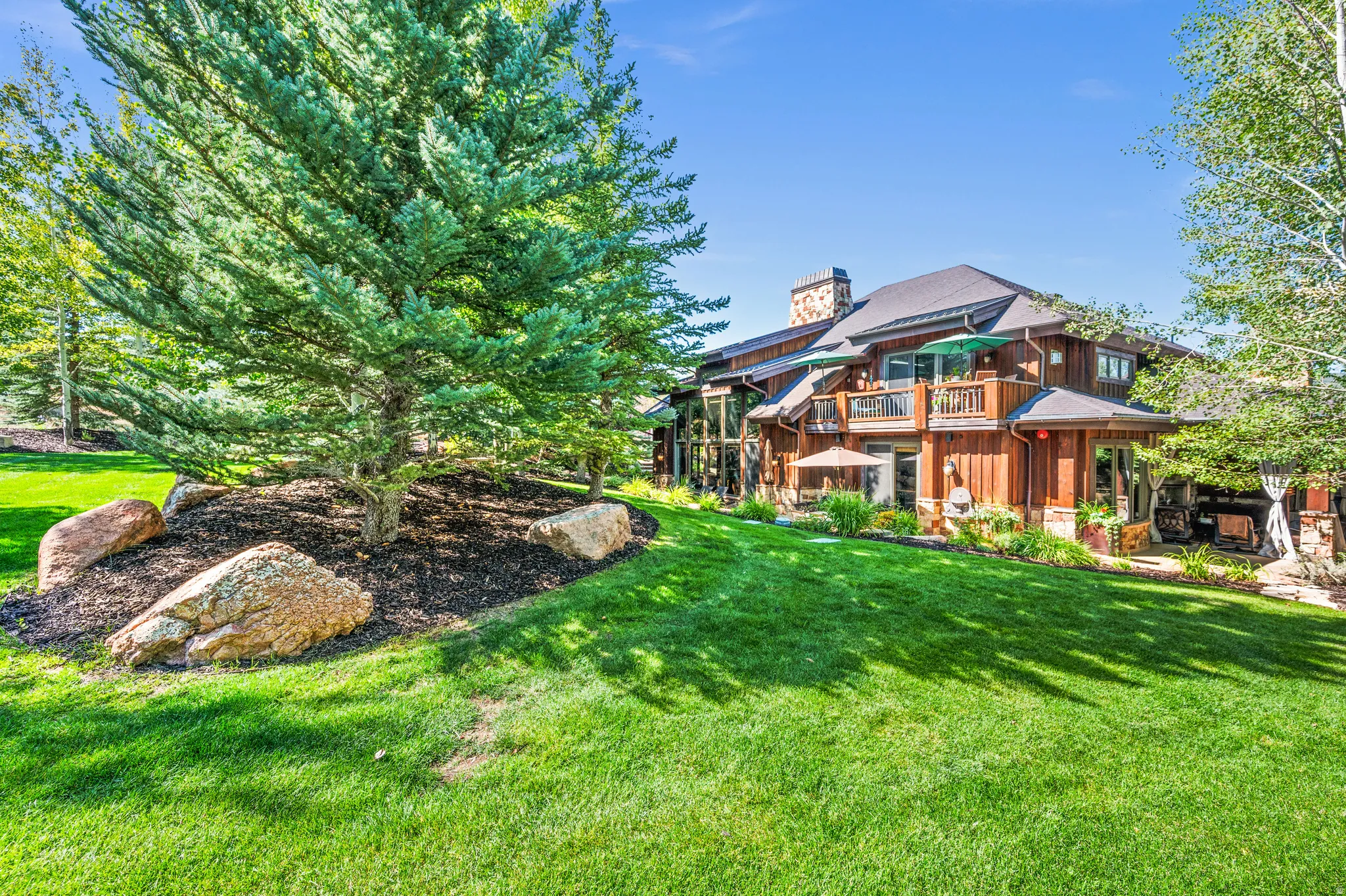 Rear view of property featuring a yard, a chimney, board and batten siding, and a balcony