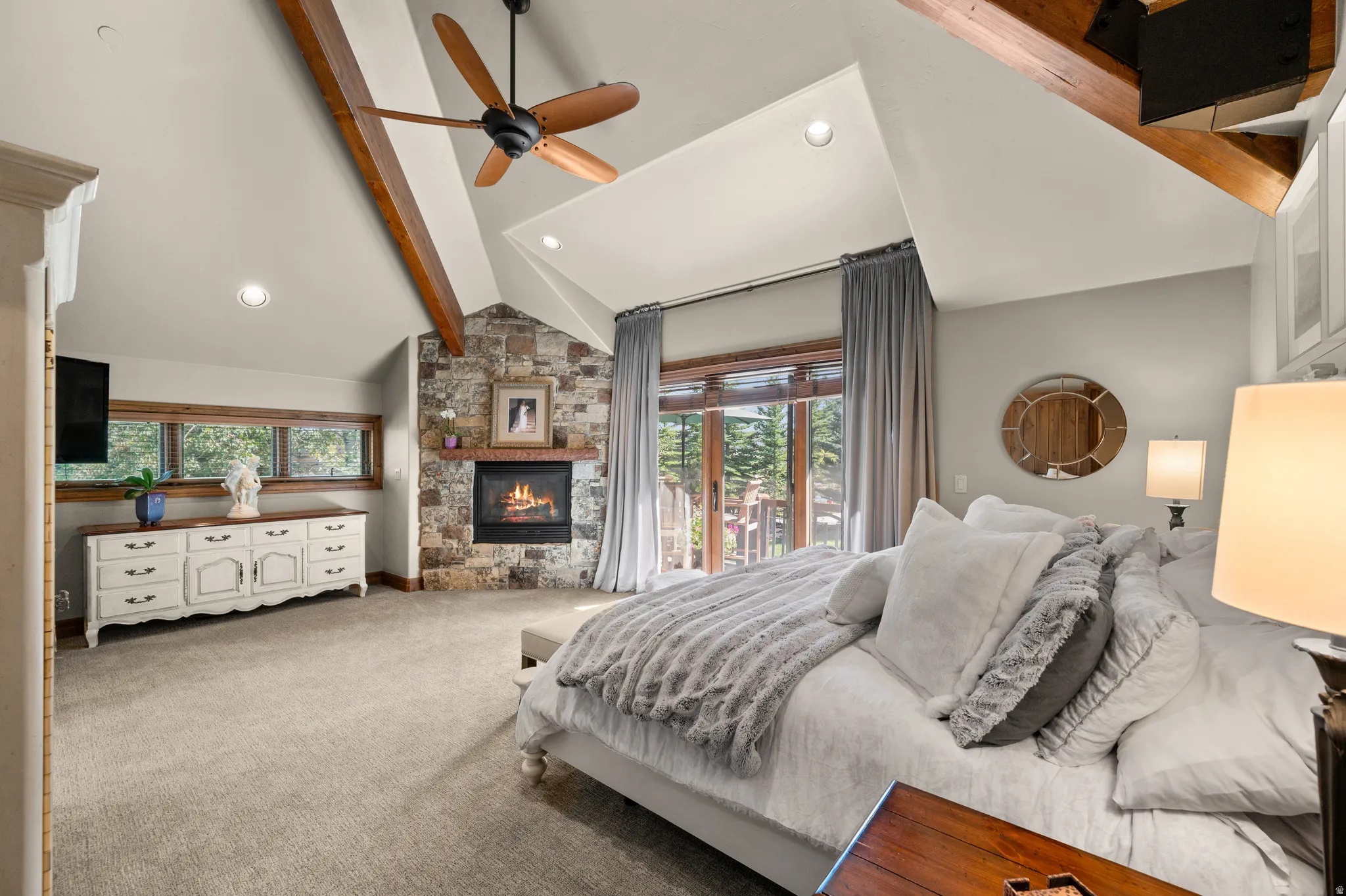 Bedroom featuring access to exterior, light carpet, ceiling fan, a stone fireplace, and recessed lighting