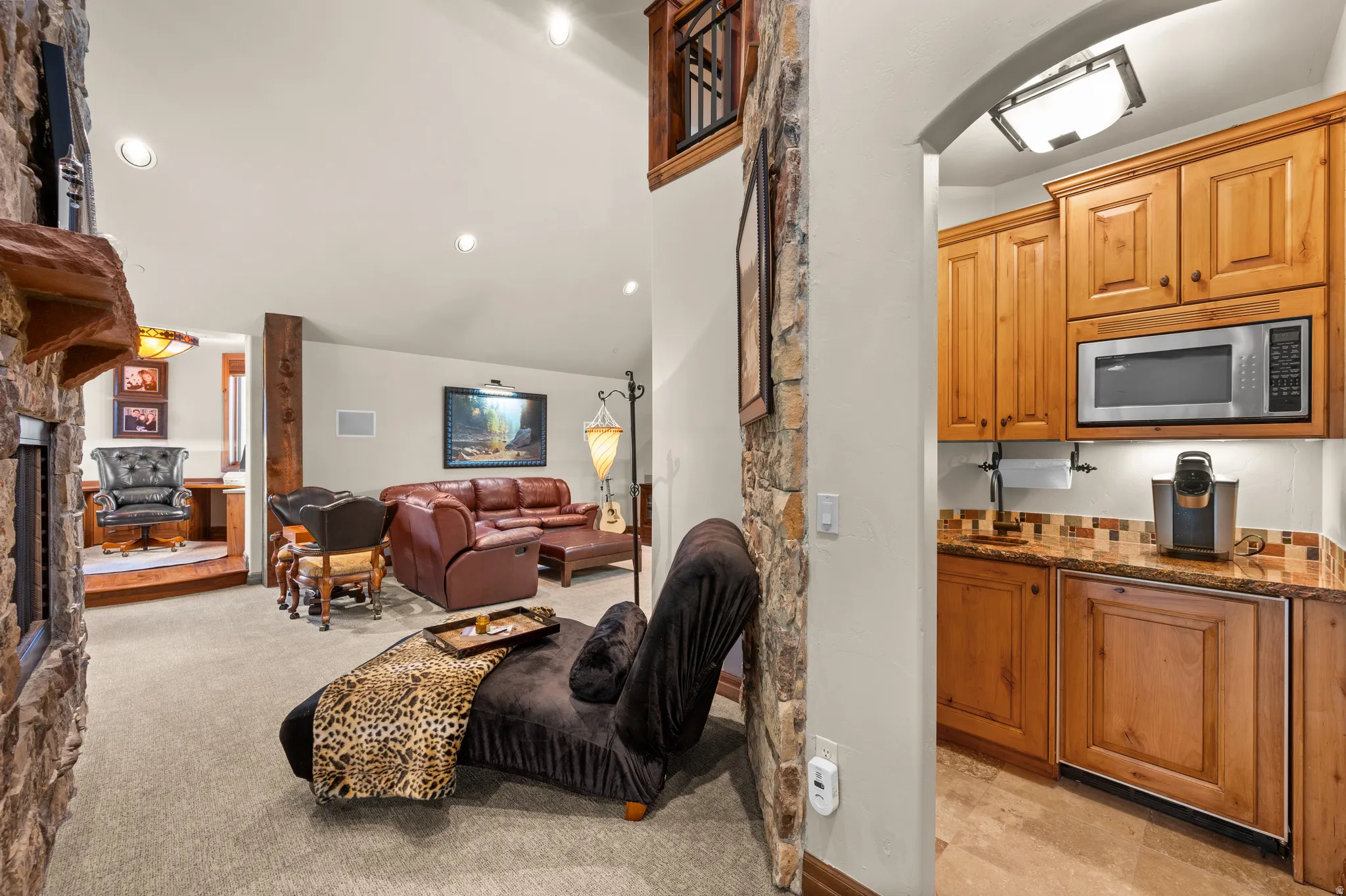Living area featuring a fireplace, vaulted ceiling, light colored carpet, arched walkways, and recessed lighting