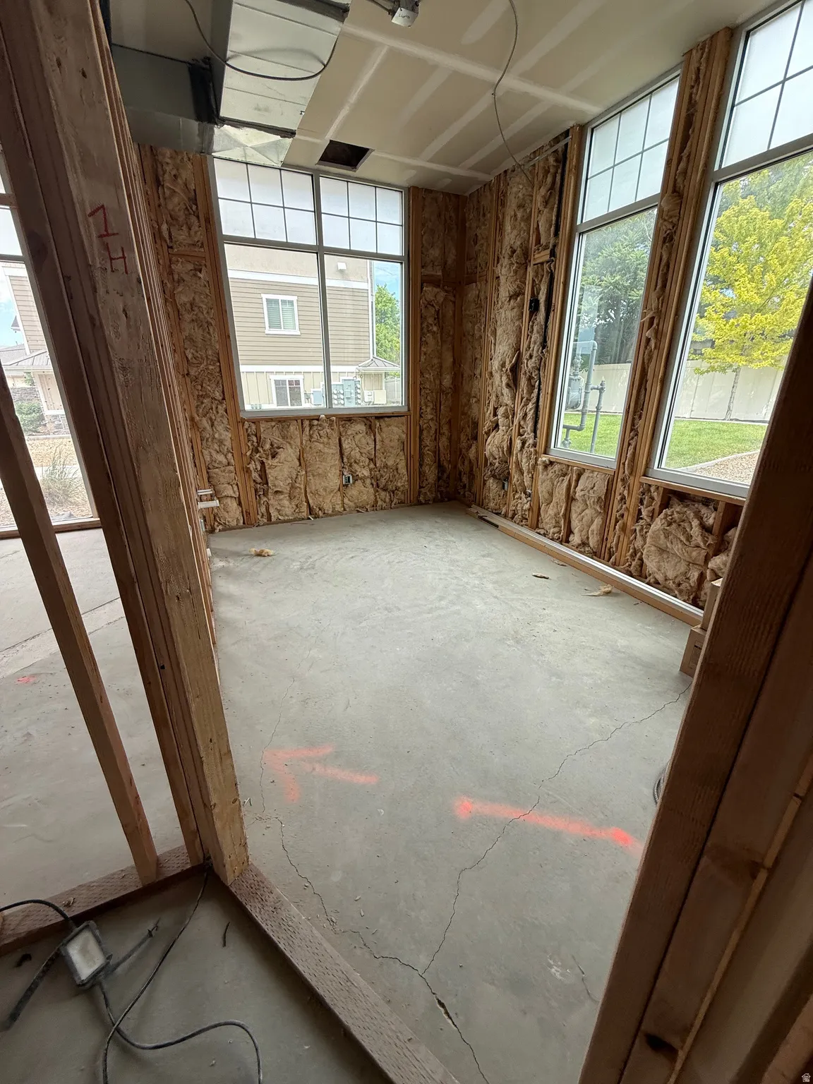 Unfinished interior space with exposed framing and insulation, featuring multiple large windows