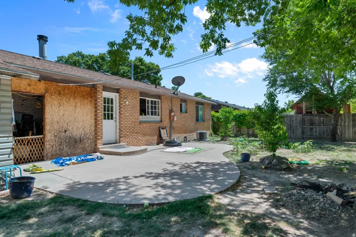 Rear exterior featuring a brick facade, white paneled door, and an expansive concrete patio