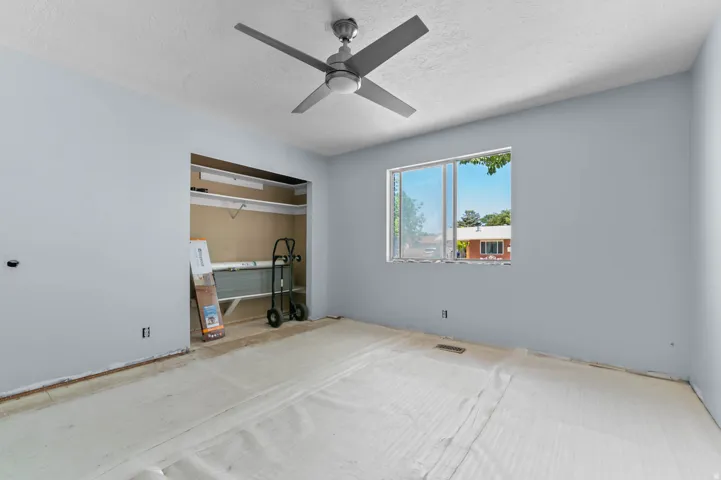 Room featuring light blue walls, a ceiling fan with integrated lighting, and a single window with a white frame