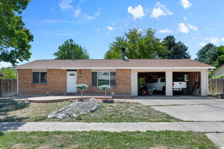 Brick exterior home featuring a two-car garage, a concrete driveway, a front entry with a white door, and a brown shingle roof