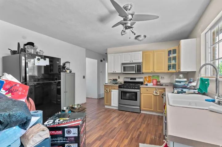 Kitchen featuring wood-finish flooring, two-toned cabinetry, stainless steel range, and a ceiling fan with integrated lighting