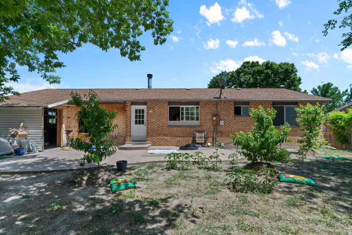 Rear exterior featuring a brick facade, multiple windows, a white paneled door, and a brown shingle roof