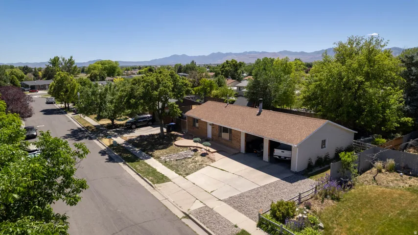 Single-story residence featuring a brown shingle roof, attached two-car carport, and a gravel and concrete driveway