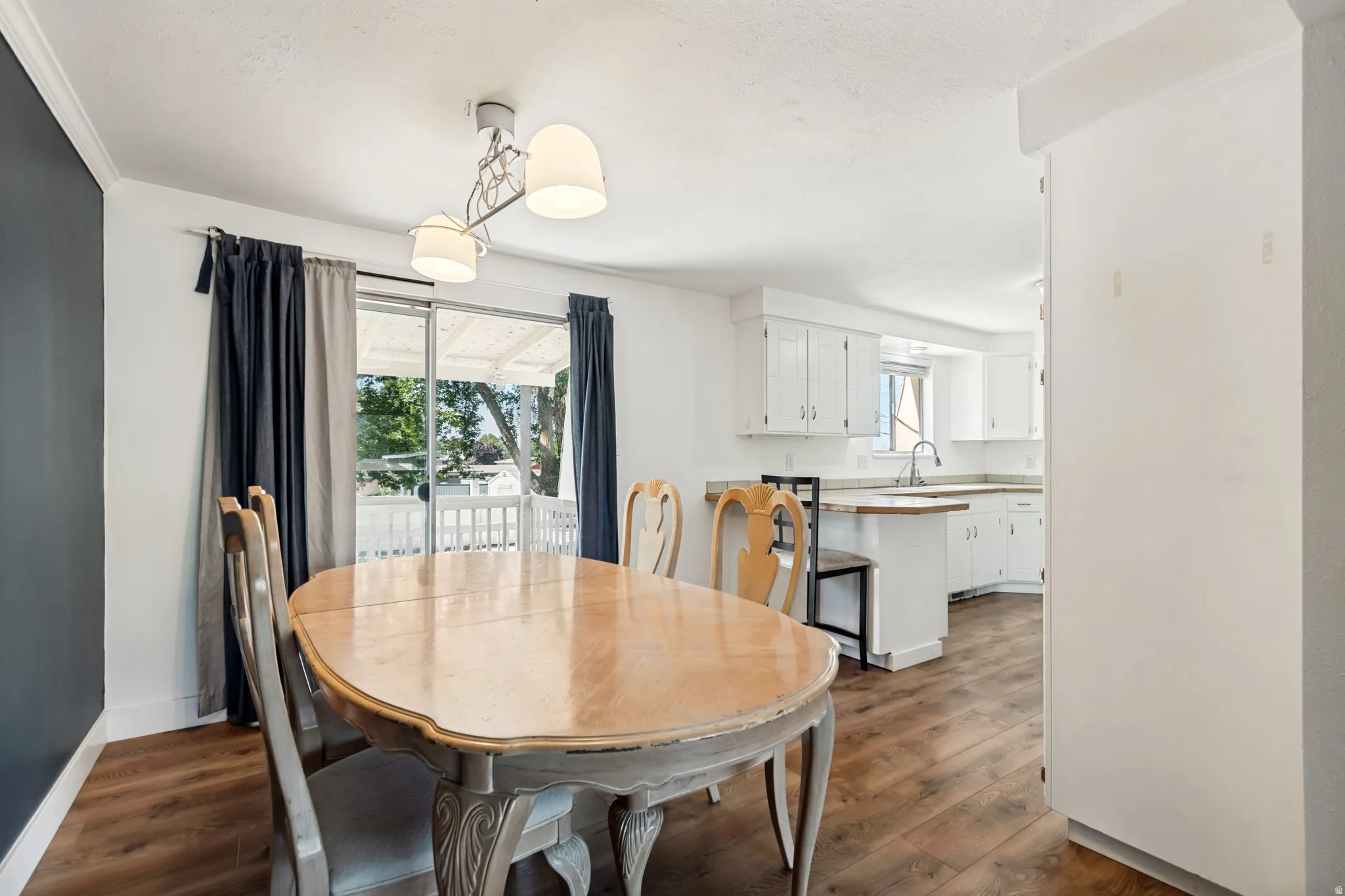 Dining area featuring wood-finish flooring, a contemporary chandelier, and a sliding glass door