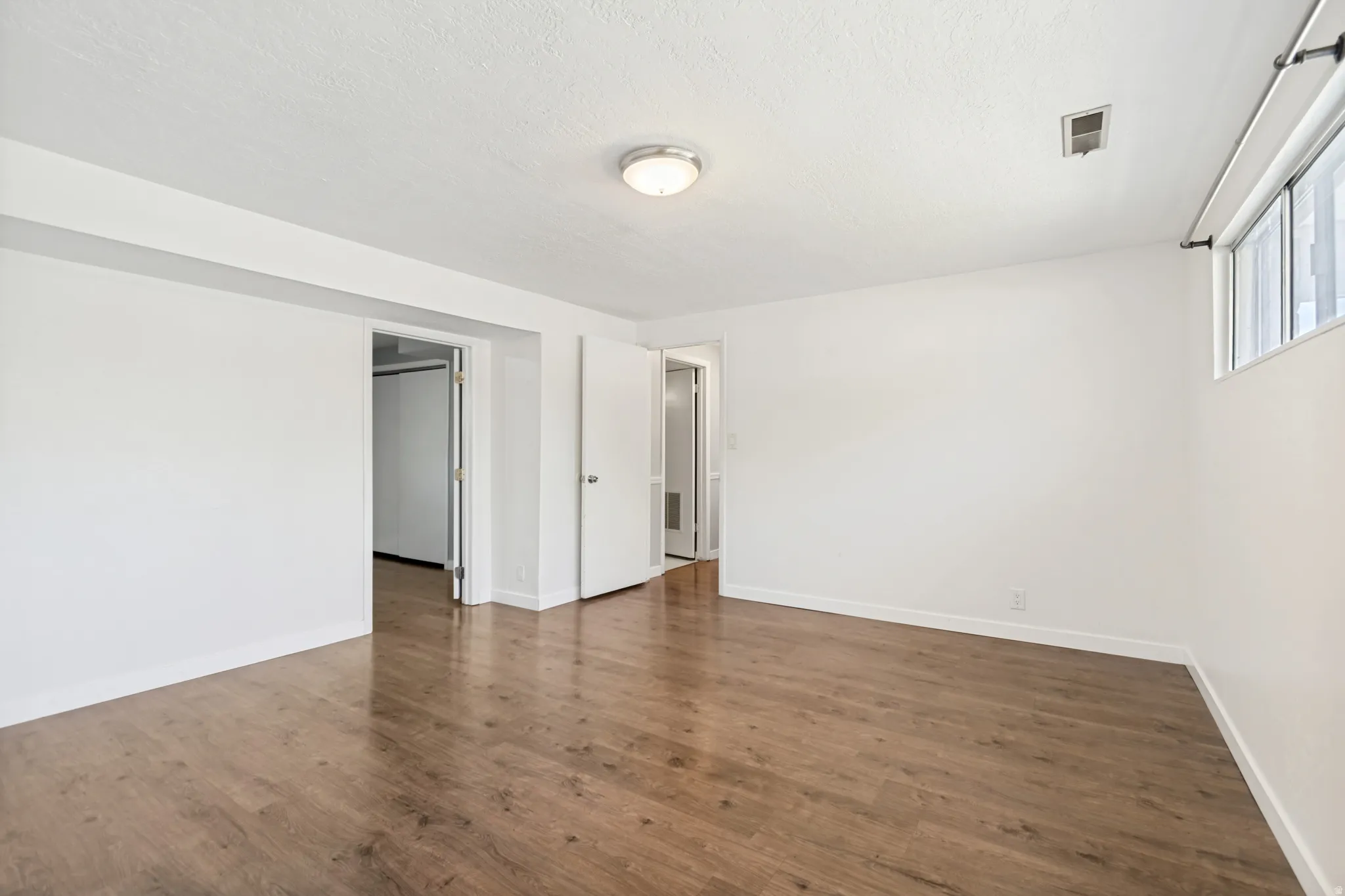 Spacious room featuring wood-finish flooring and a neutral color palette
