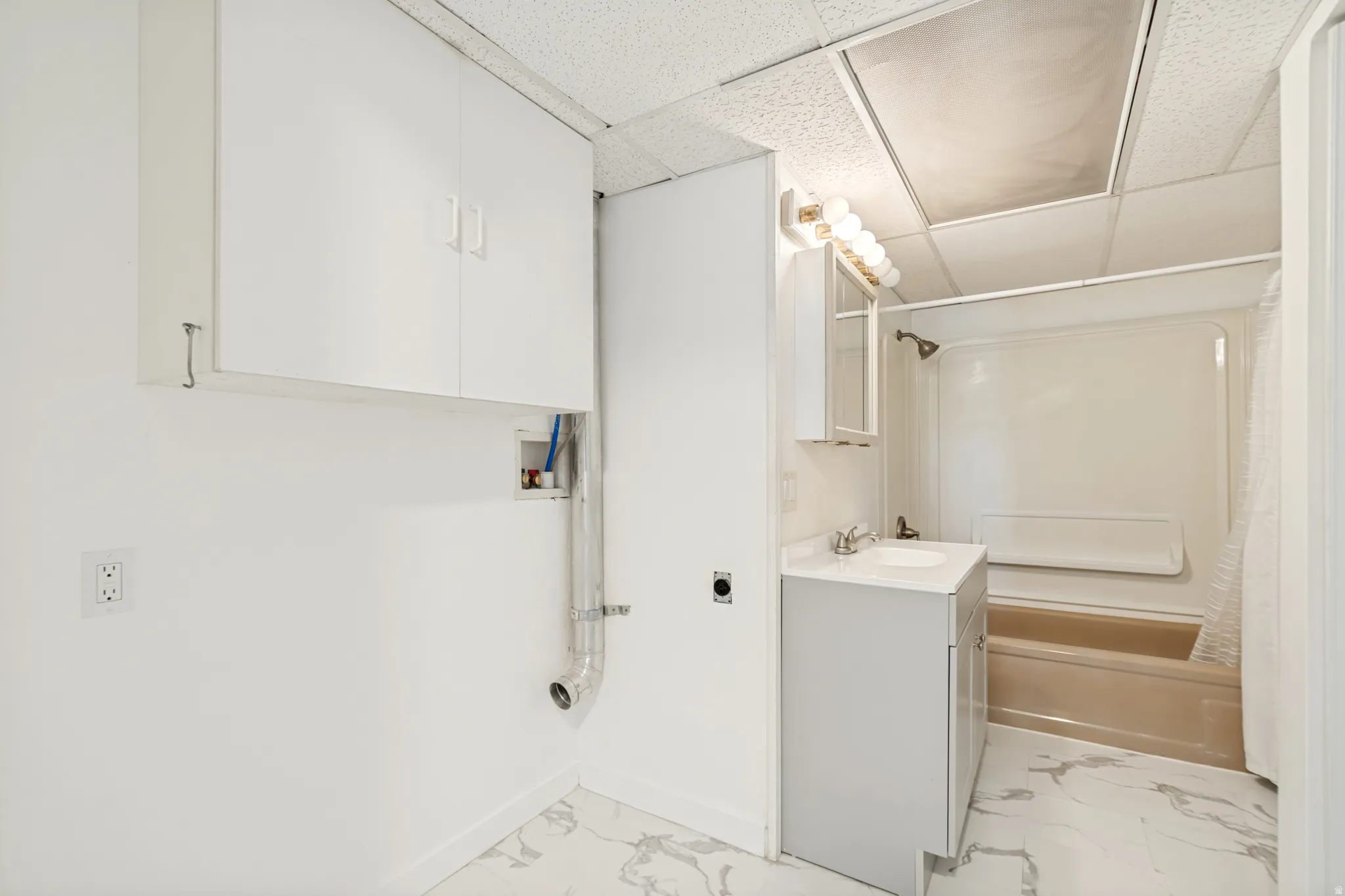 Full bathroom with a single vanity, a shower-over-tub combination, and white wall cabinetry