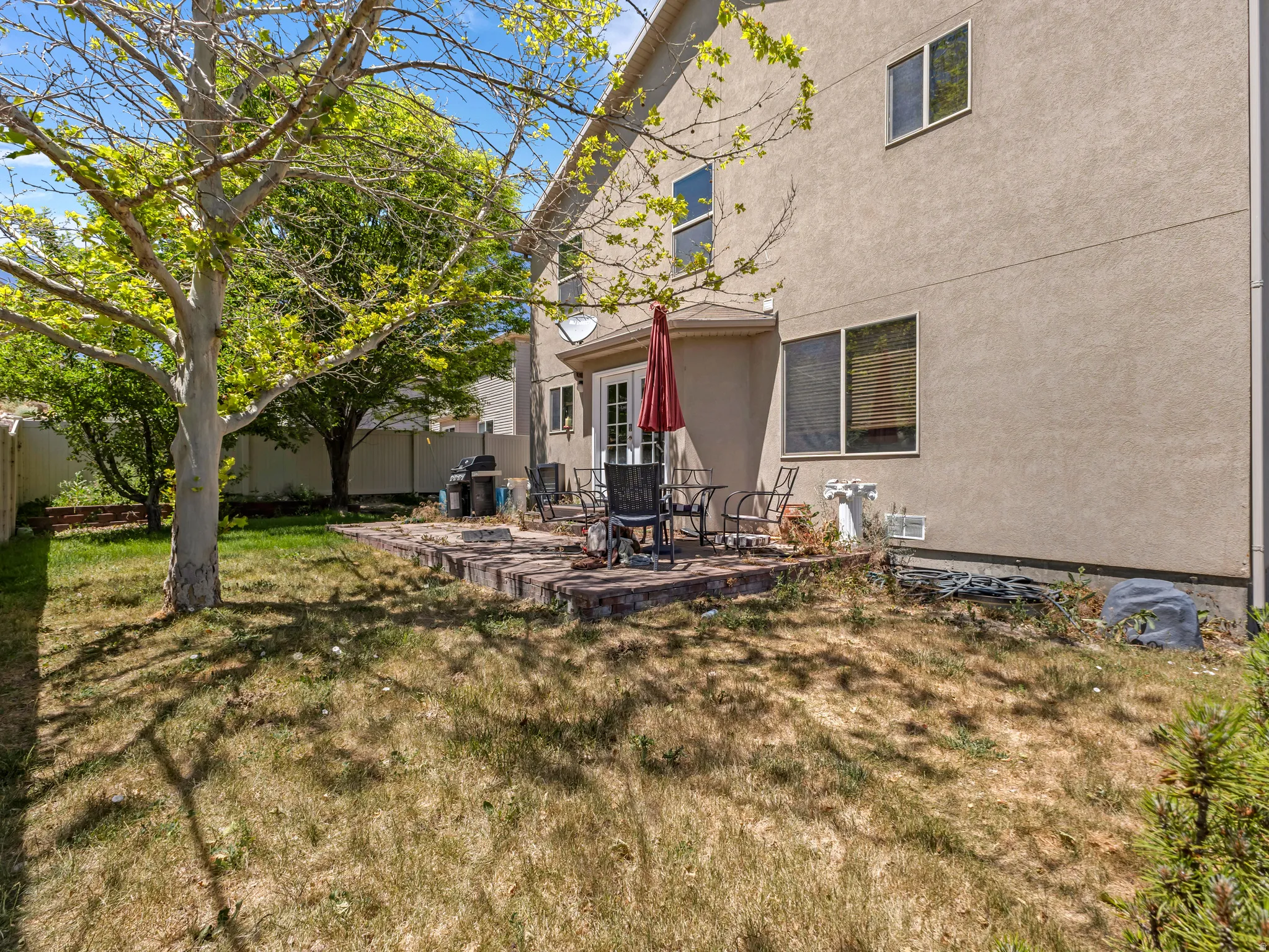 Rear exterior with a patio, mature trees, and a privacy fence