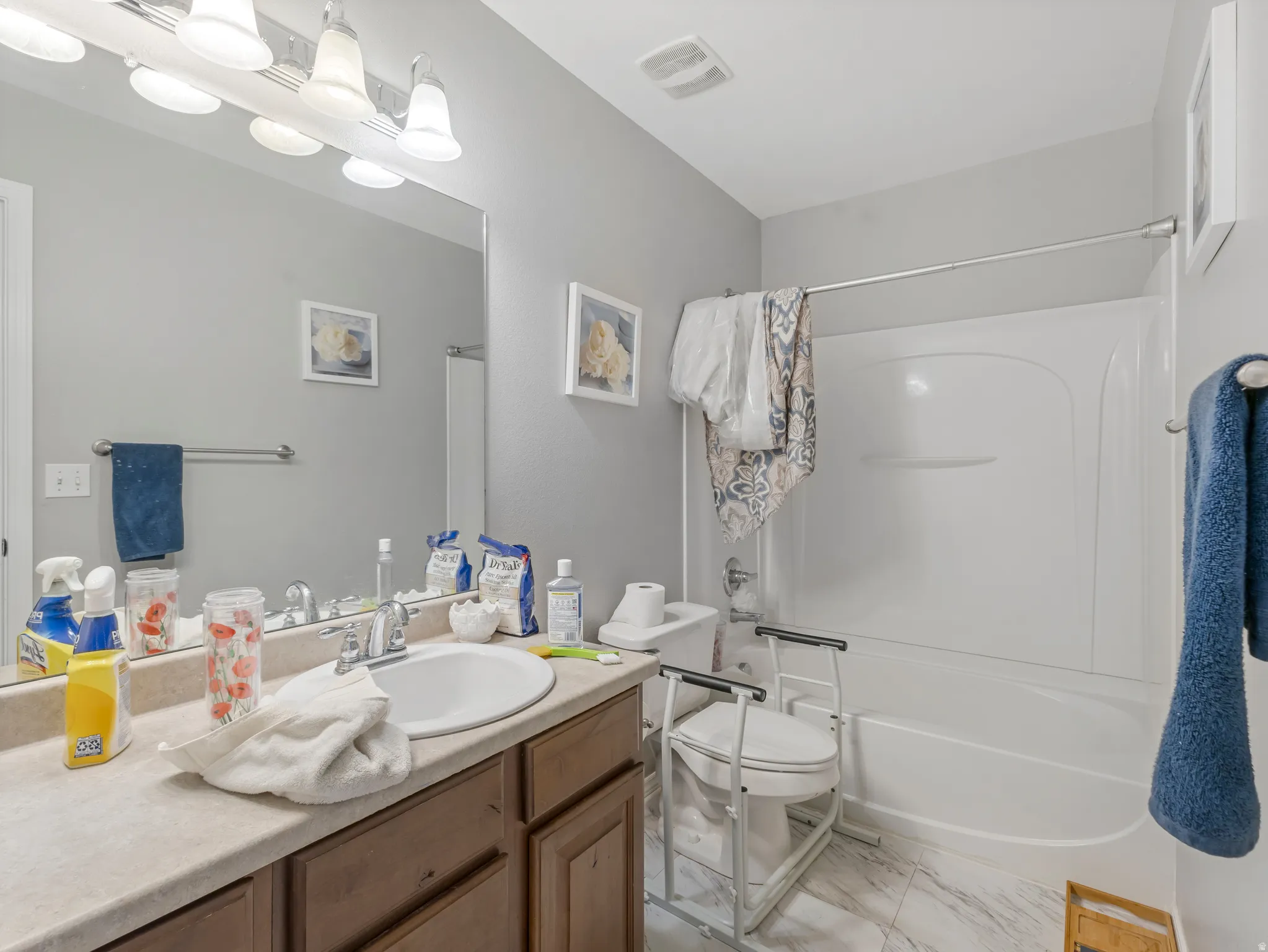 Bathroom featuring a single vanity with a laminate countertop, an integrated sink, and a chrome faucet