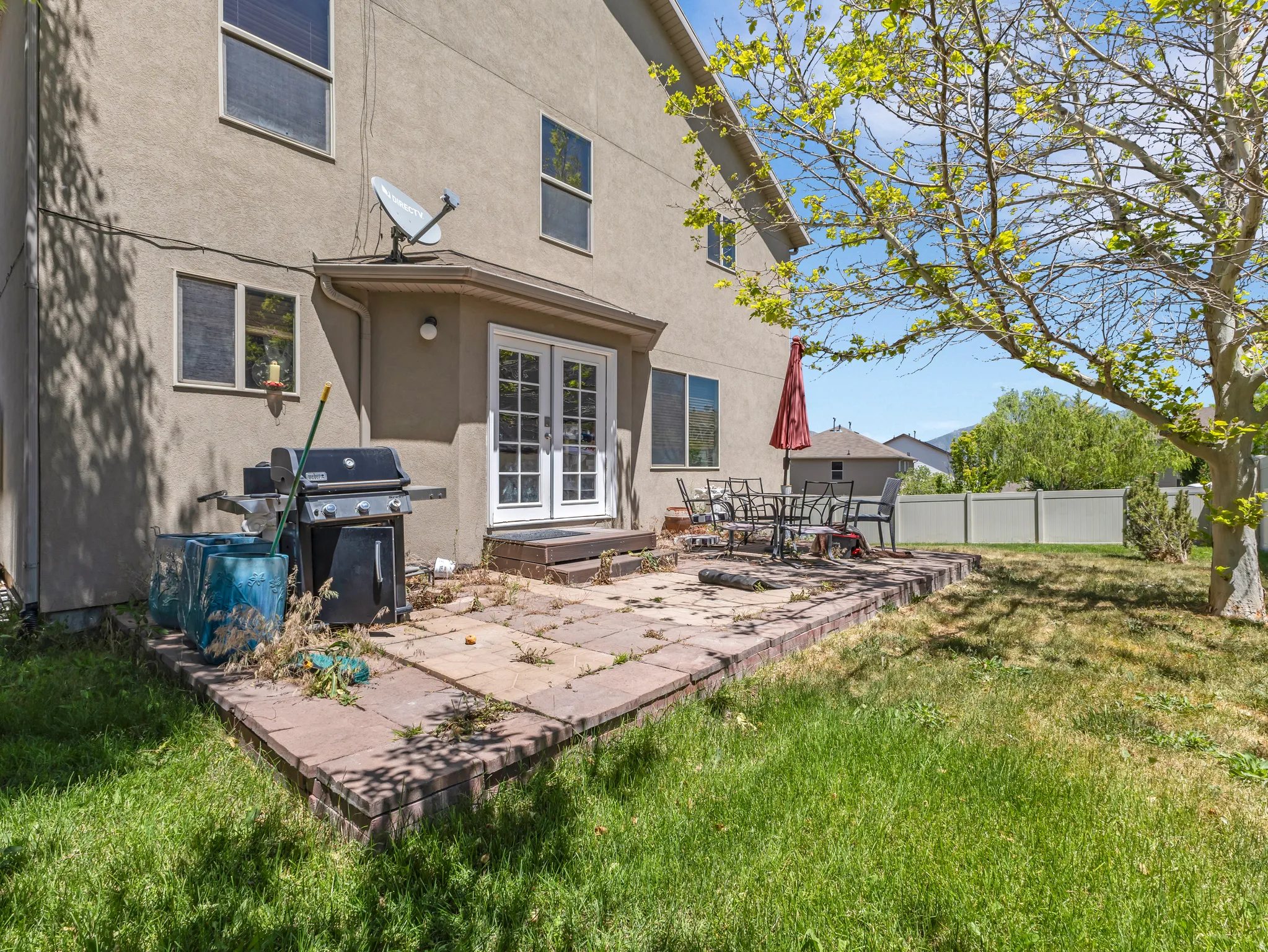 Rear exterior featuring a stone paver patio, double glass-paned doors, and a stucco finish