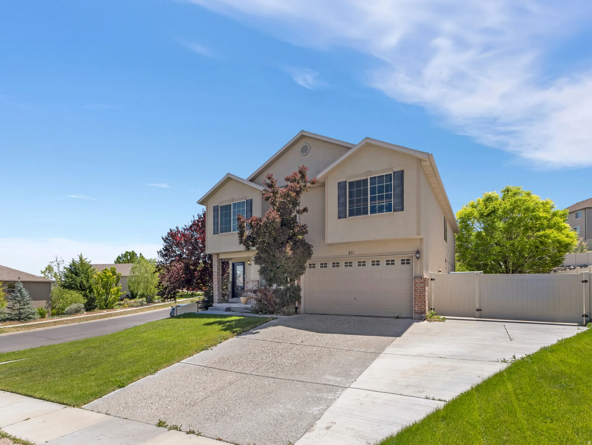Two-story residence featuring a neutral stucco exterior, a two-car garage with panel detailing, and a concrete driveway