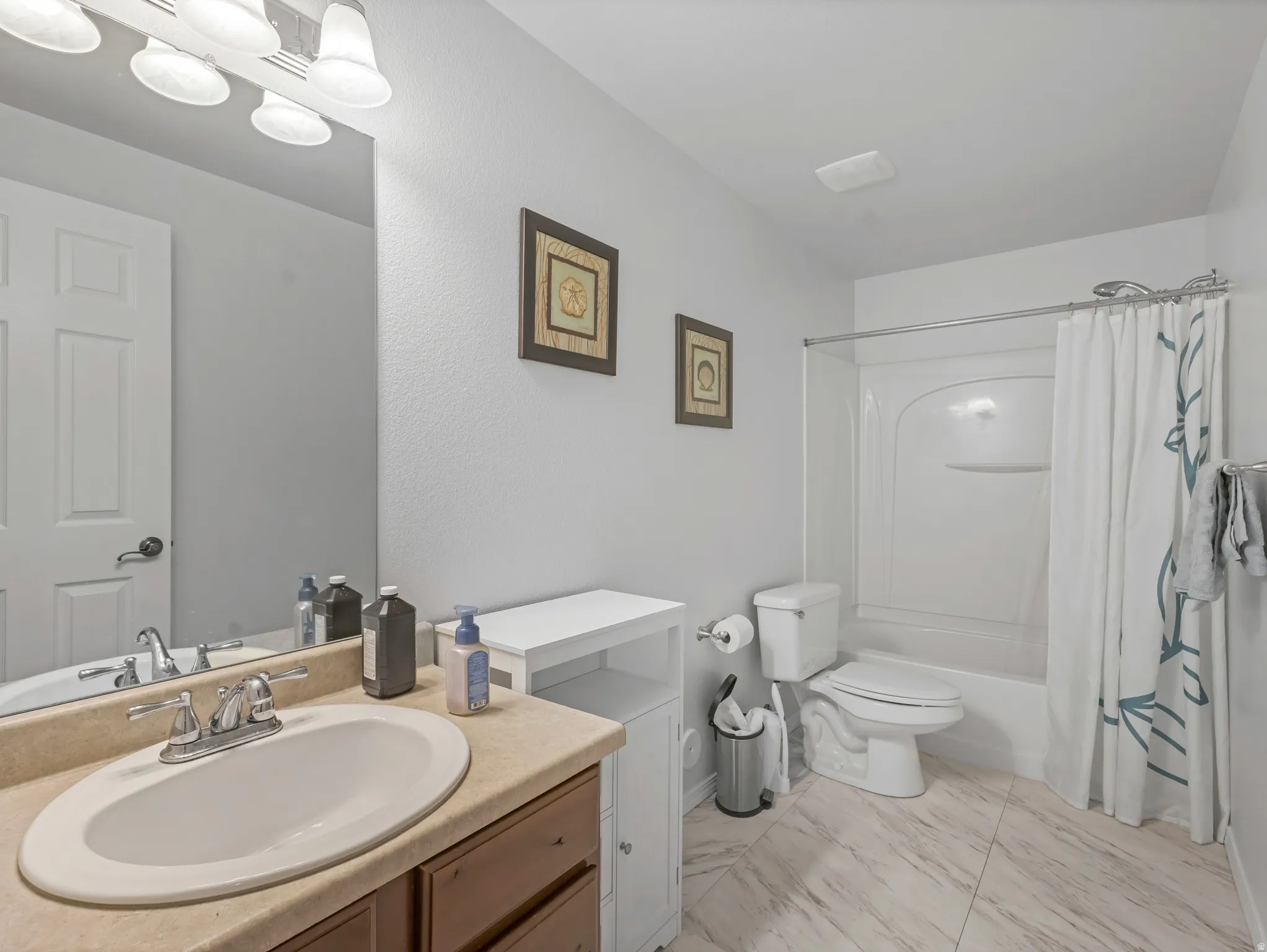 Full bathroom featuring a single vanity with an oval undermount sink, a countertop, and a chrome faucet