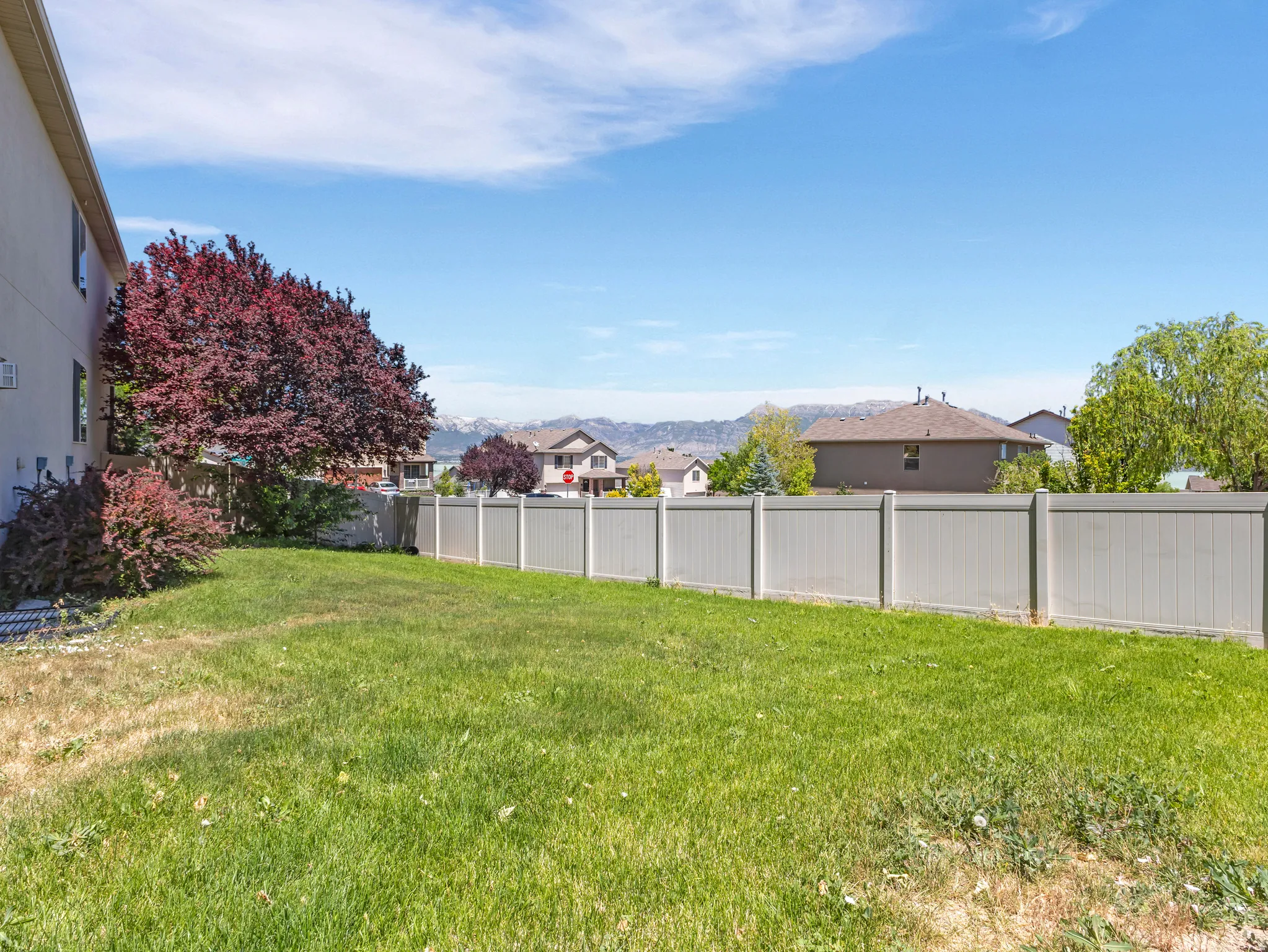 Expansive yard featuring a manicured lawn, a privacy fence, and mature landscaping