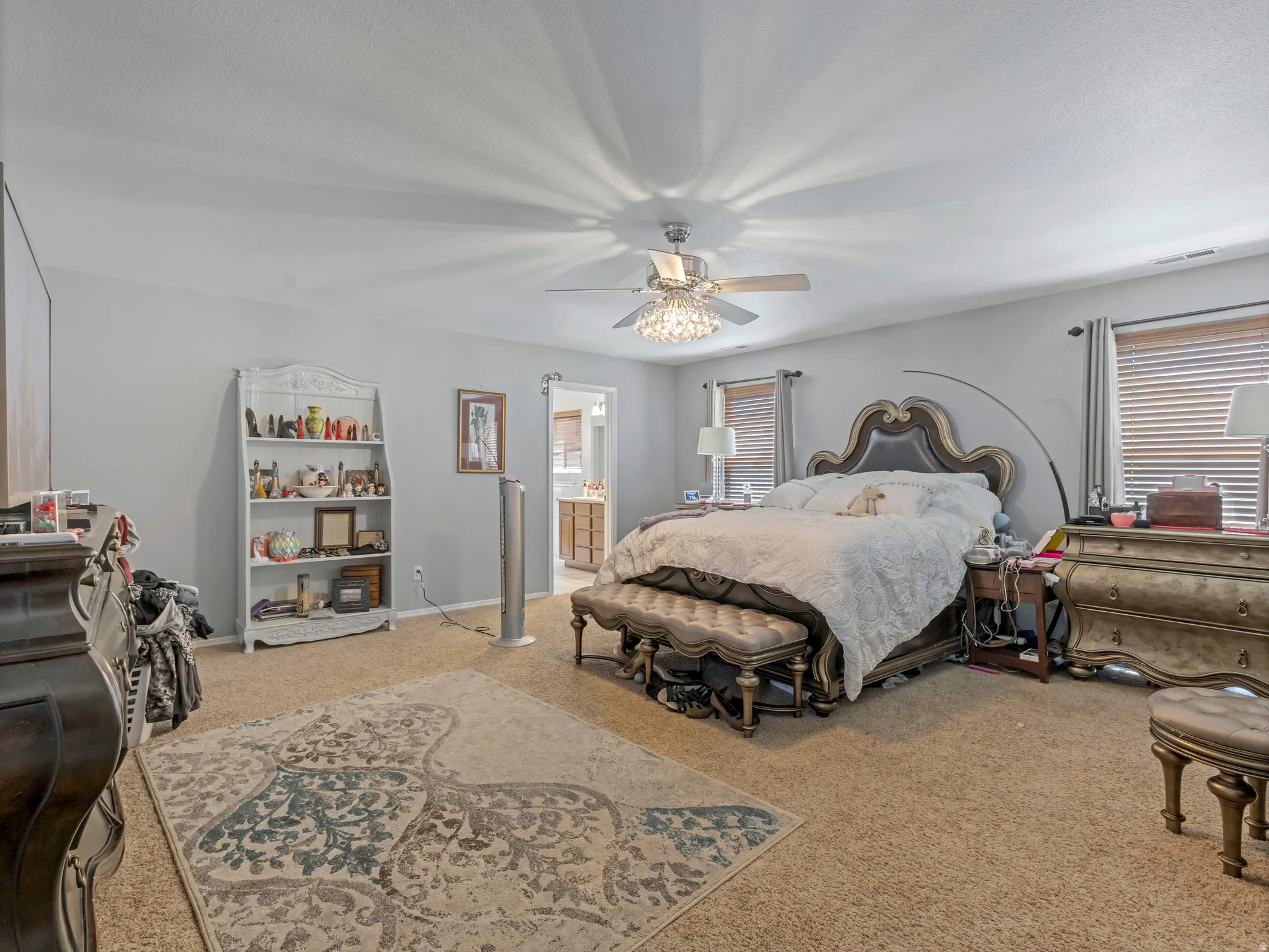 Carpeted bedroom with neutral wall tones and a ceiling fan with integrated lighting
