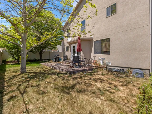 Rear exterior with a patio, mature trees, and a privacy fence