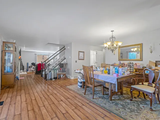 Wood-finish flooring throughout, featuring a staircase with white risers and dark banister
