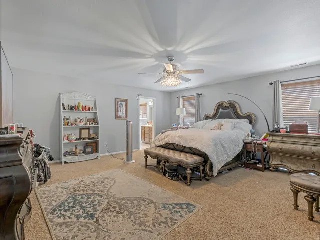 Carpeted bedroom with neutral wall tones and a ceiling fan with integrated lighting