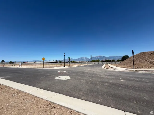 Paved street with concrete curbing, street light, and distant mountain scenery
