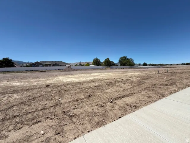 Expansive vacant lot featuring a cleared, level surface and a paved sidewalk