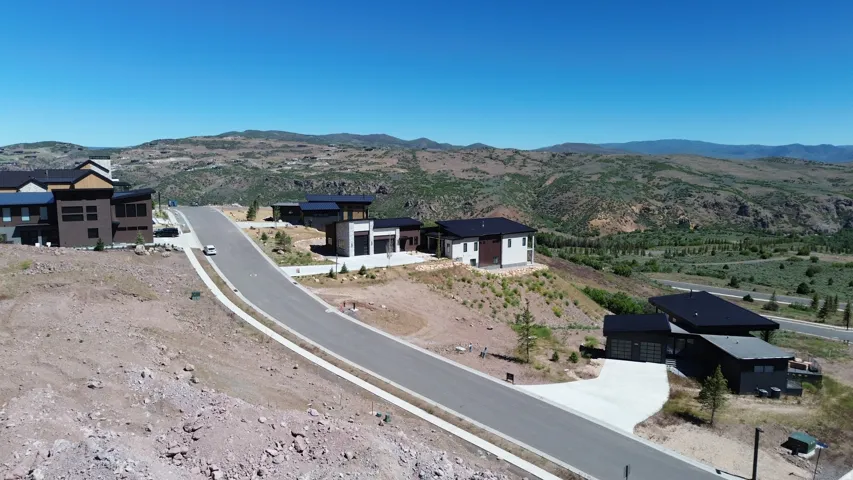Hillside residential development featuring modern architecture, paved roads, and natural landscape