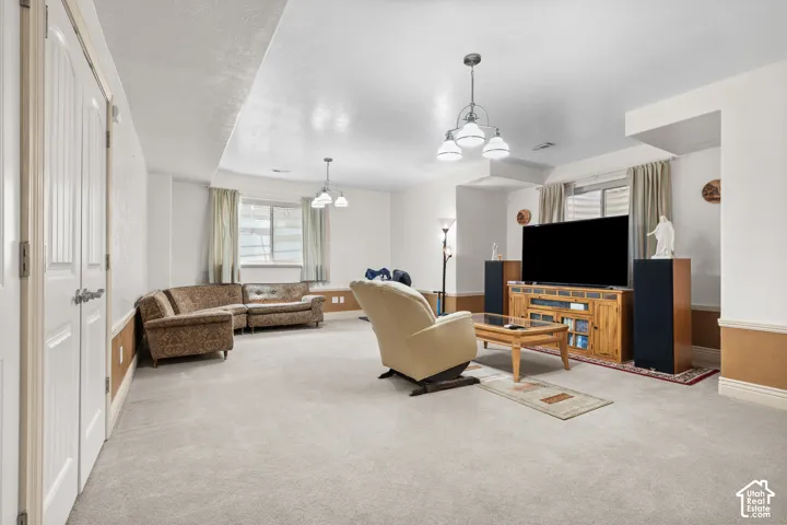 Spacious lower-level living area with light-colored carpeting, multiple windows, recessed lighting. The white and beige color scheme offers plenty of brightness