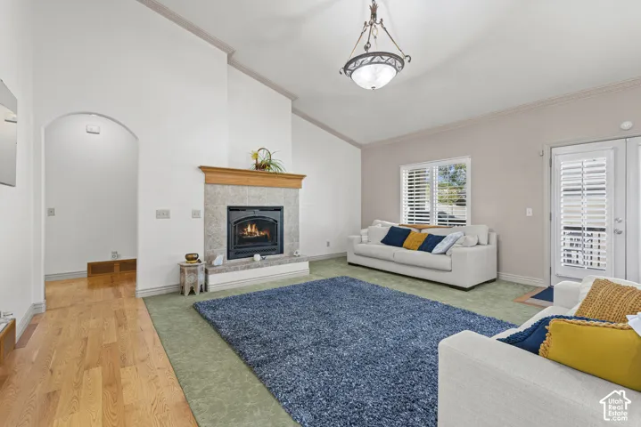 Living area featuring a fireplace with a stone surround and wood mantel, vaulted ceiling, and hardwood flooring
