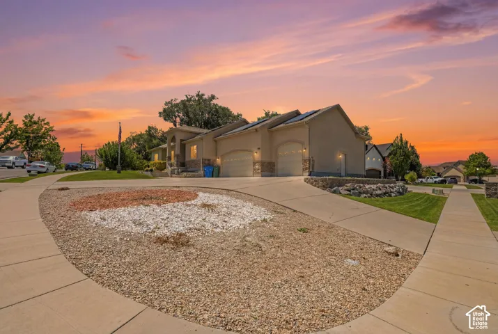 Stucco exterior home featuring a three-car garage with arched entrances, stone accents, and solar panels