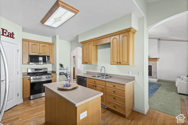 Kitchen featuring wood-finish cabinetry, new stainless steel appliances, a center island with countertop, and wood-finish flooring