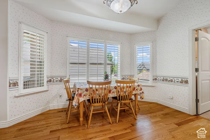 Bay window with plantation shutters, wood-finish flooring, and crown molding