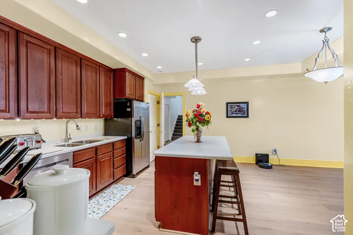 Open-concept kitchen featuring wood-finish flooring, recessed lighting, and a kitchen island with seating