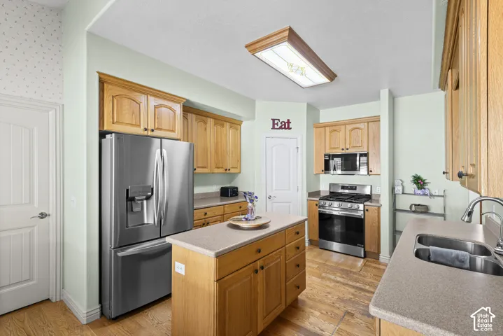 Kitchen with wood-finish flooring, light wood cabinetry, Brand New stainless steel appliances, and a central island