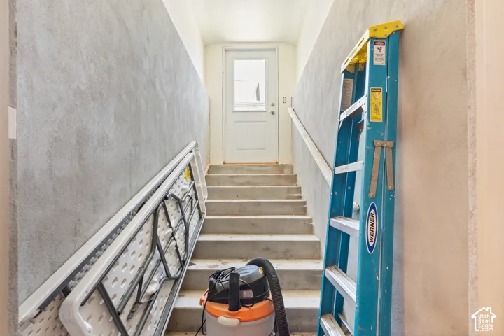 Basement entrance stairwell with concrete steps and handrail