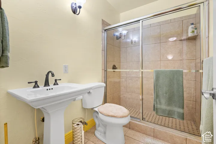 Bathroom featuring a pedestal sink, a tiled shower with glass enclosure, and a built-in shower niche