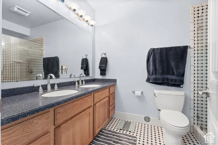 Dual vanity with light wood cabinetry and dark speckled countertops