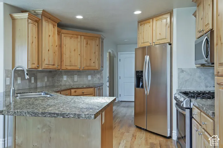 Kitchen featuring light wood cabinetry with crown molding, stone-finish countertops, and a coordinating stone-finish backsplash