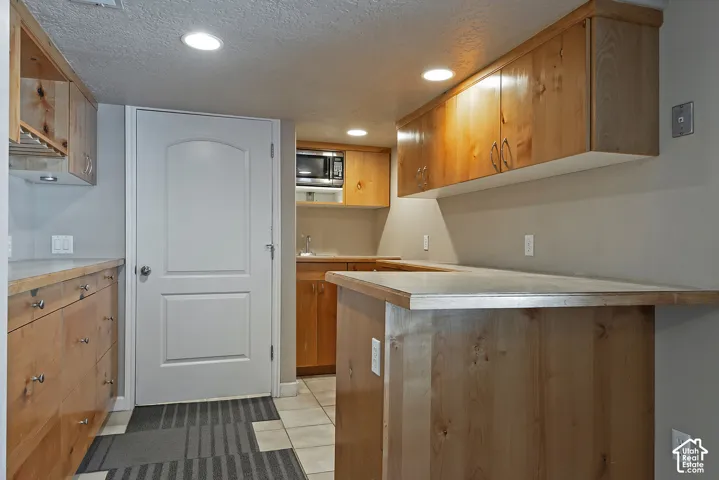 Kitchenette featuring custom wood cabinetry, a built-in microwave, and recessed lighting