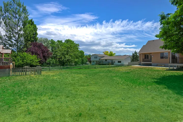 Expansive grassy yard with mature trees and a wood picket fence