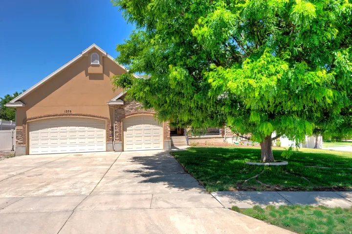Stucco and stone facade home featuring a two-car garage, an additional single-car garage, and a concrete driveway