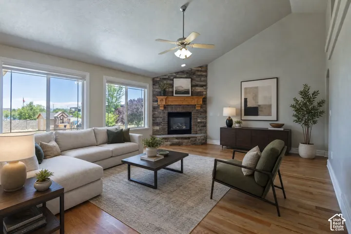 Living area featuring a stone fireplace with a wood mantel, vaulted ceiling, and wood-finish flooring