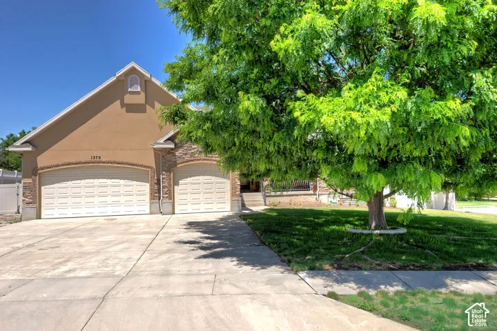 Stucco and stone facade home featuring a two-car garage, an additional single-car garage, and a concrete driveway