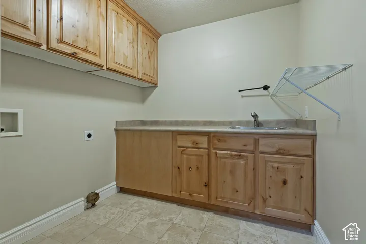 Utility room with wood-finish cabinetry, a built-in sink, and tile flooring