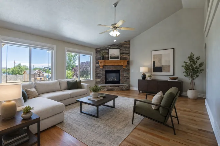 Living area featuring a stone fireplace with a wood mantel, vaulted ceiling, and wood-finish flooring